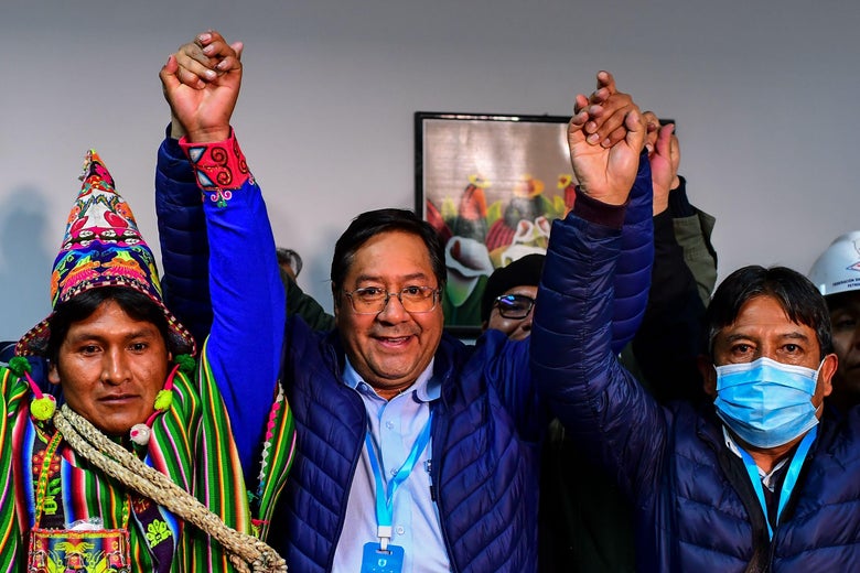 Arce stands in the center with raised arms, holding hands with two allies in celebration
