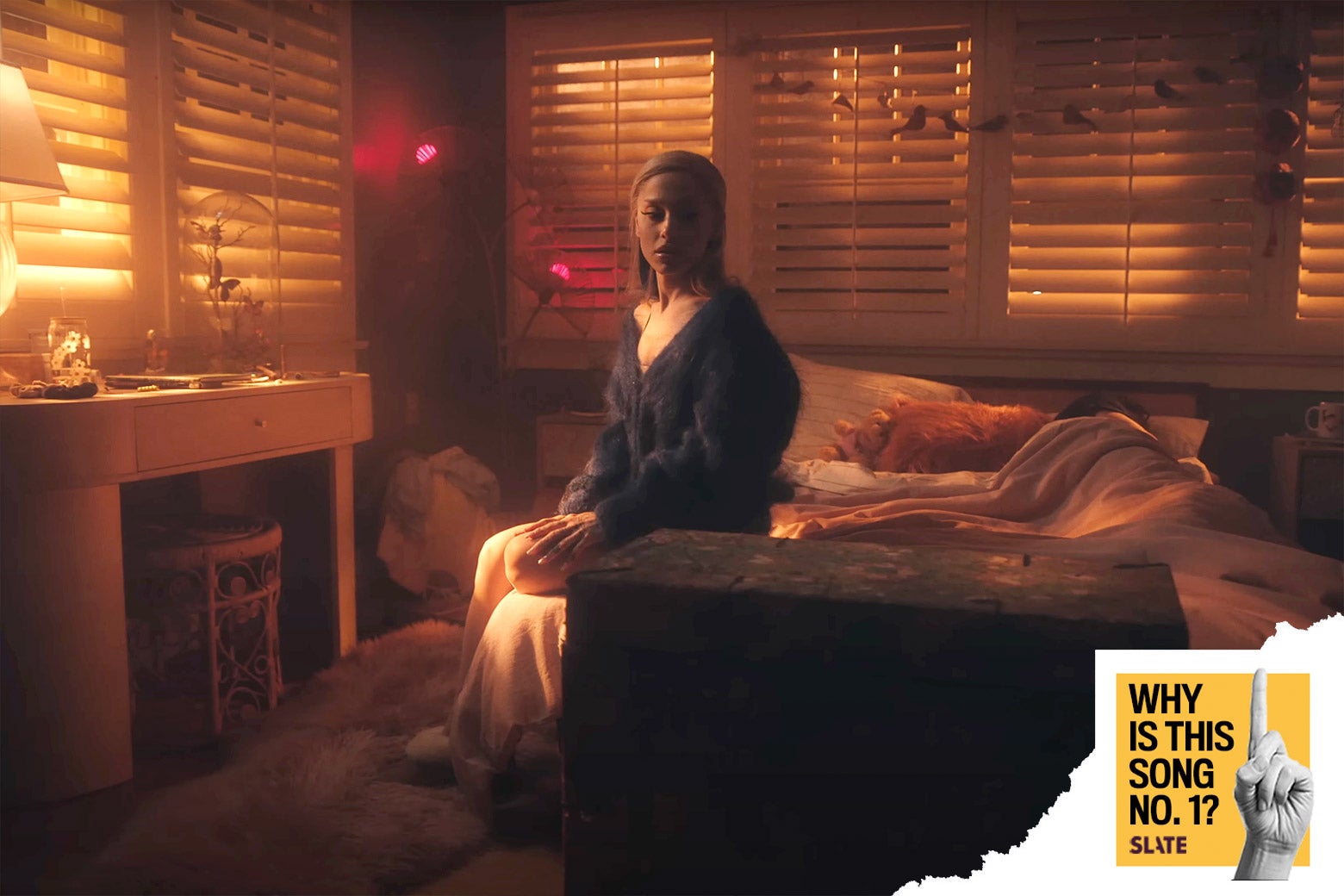 A still shows the singer sitting on the side of the bed in the morning light with another figure still asleep behind her. In the corner a logo reads 