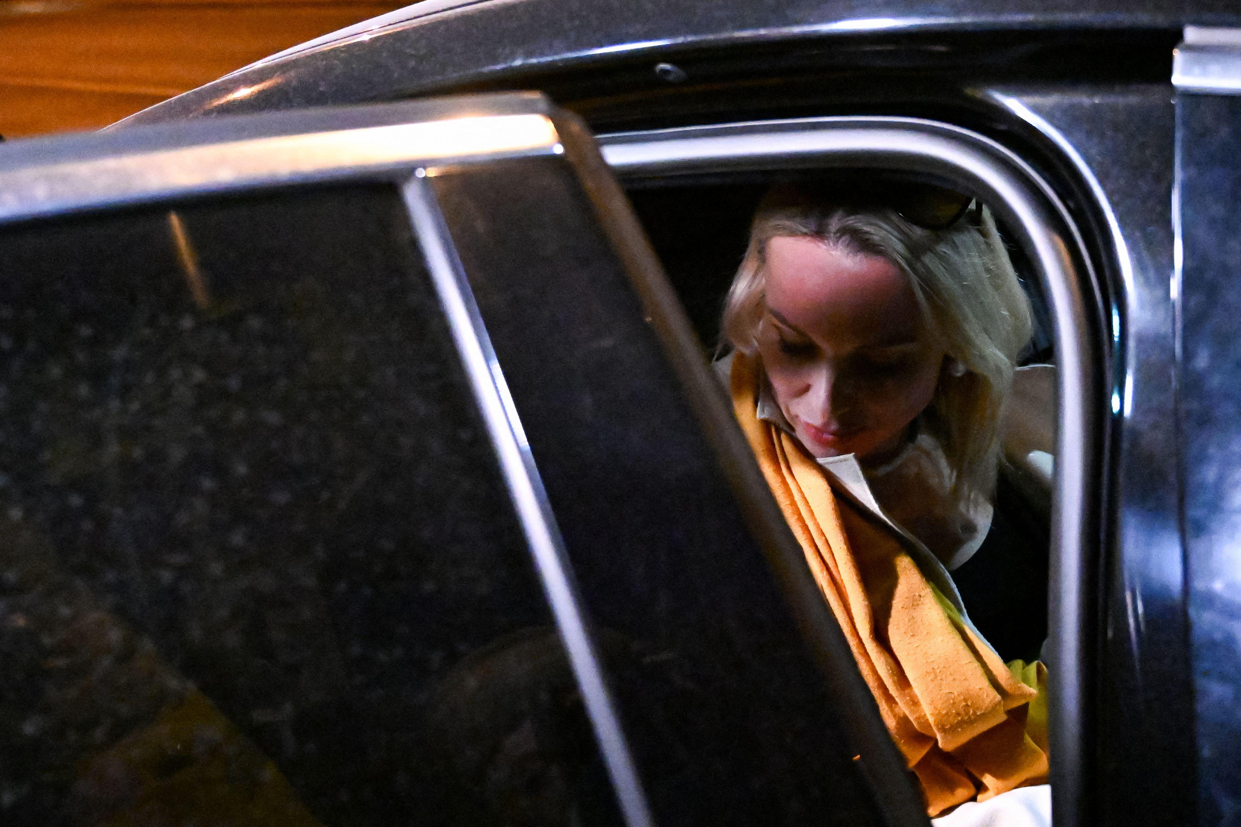 A woman sits in a car with the door half-open.