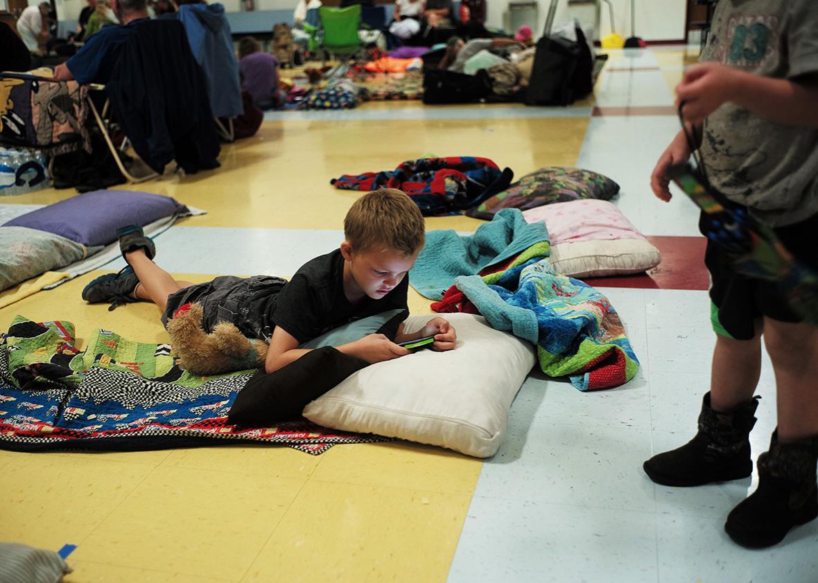 Shawn Miller plays on a cell phone laying on the floor of a makeshift shelter at the Timberlin Creek Elementary School in St. Augustine, Florida, on October 6, 2016, ahead of hurricane Matthew.