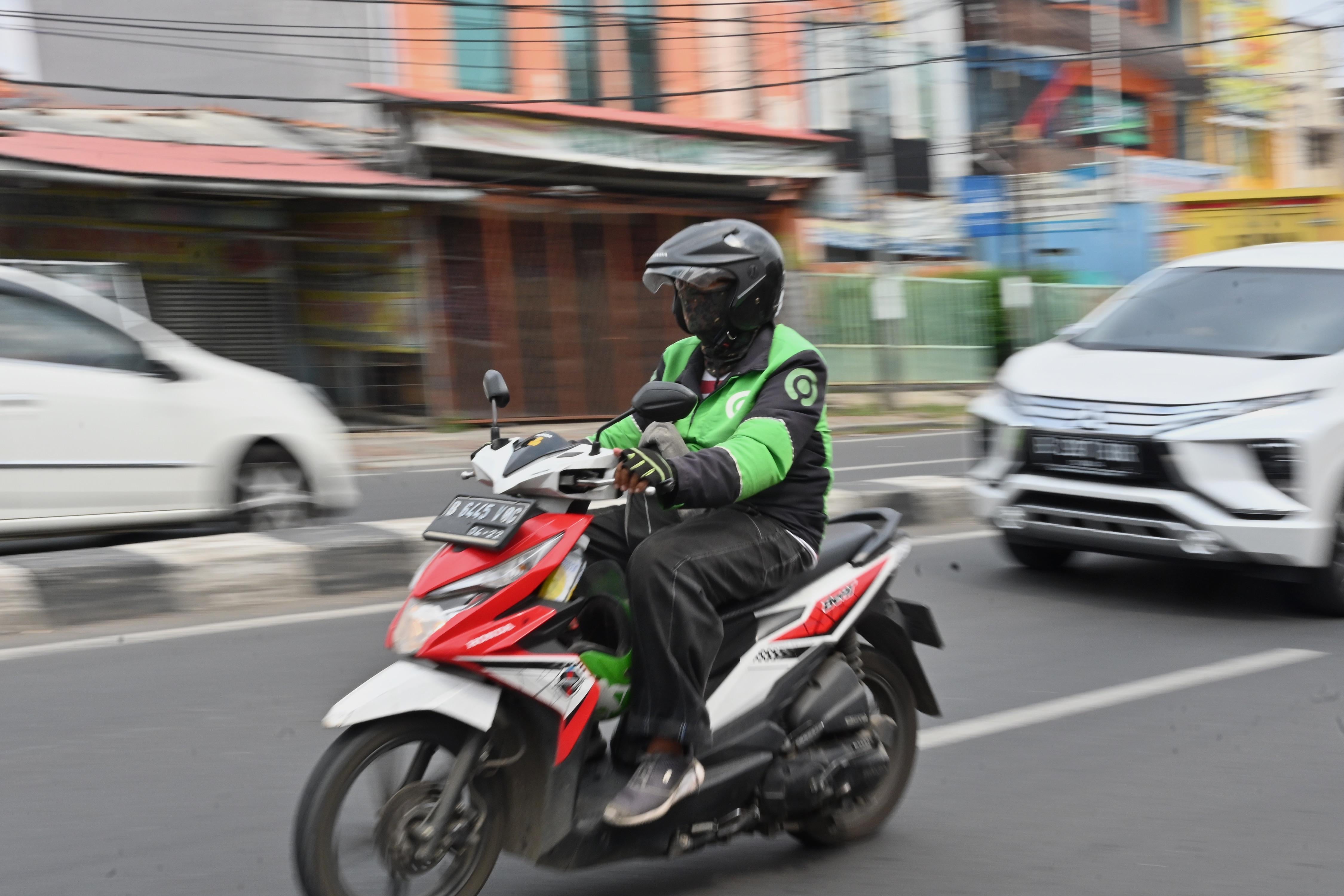 A person on a motorbike drives down a street.