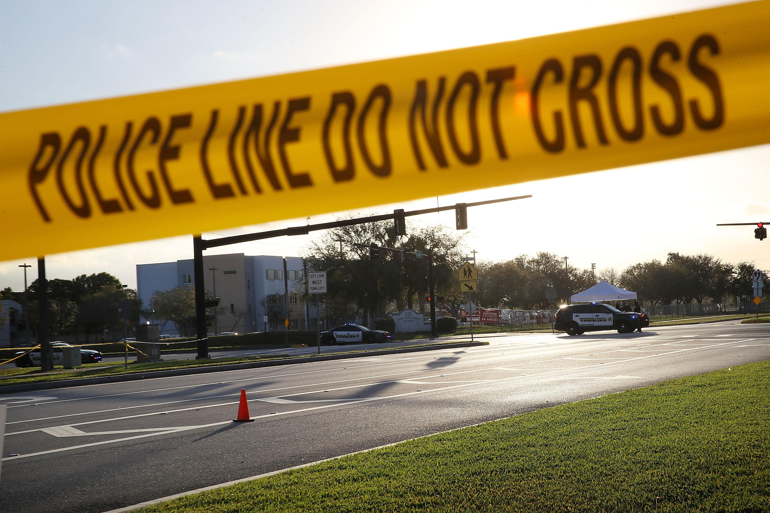 Police and caution tape reading "Police Line Do Not Cross" in front of Marjory Stoneman Douglas High School in Parkland, Florida