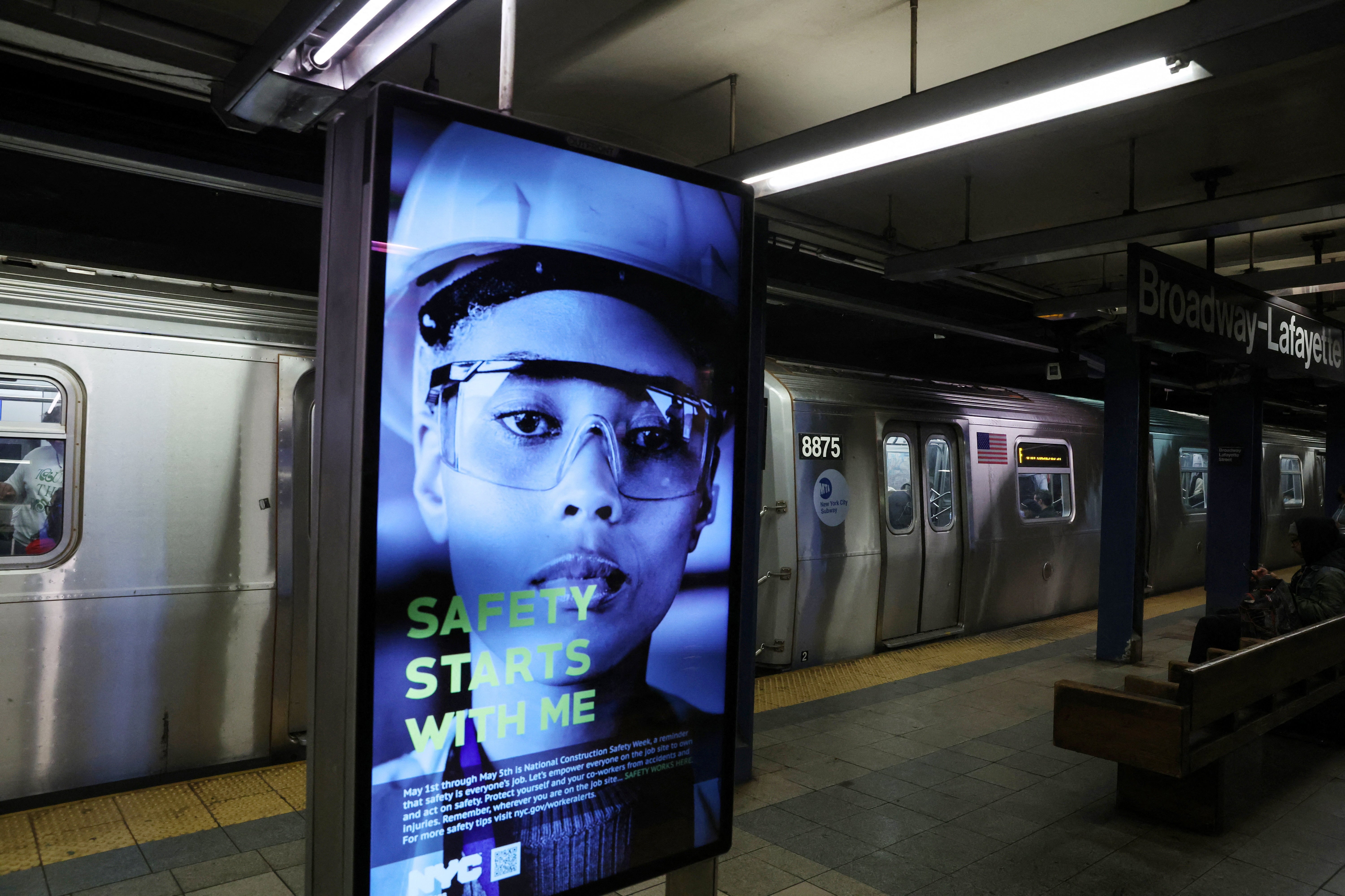 The Broadway-Lafayette subway platform in Manhattan showing an MTA employee on a sign reading "Safety starts with me."