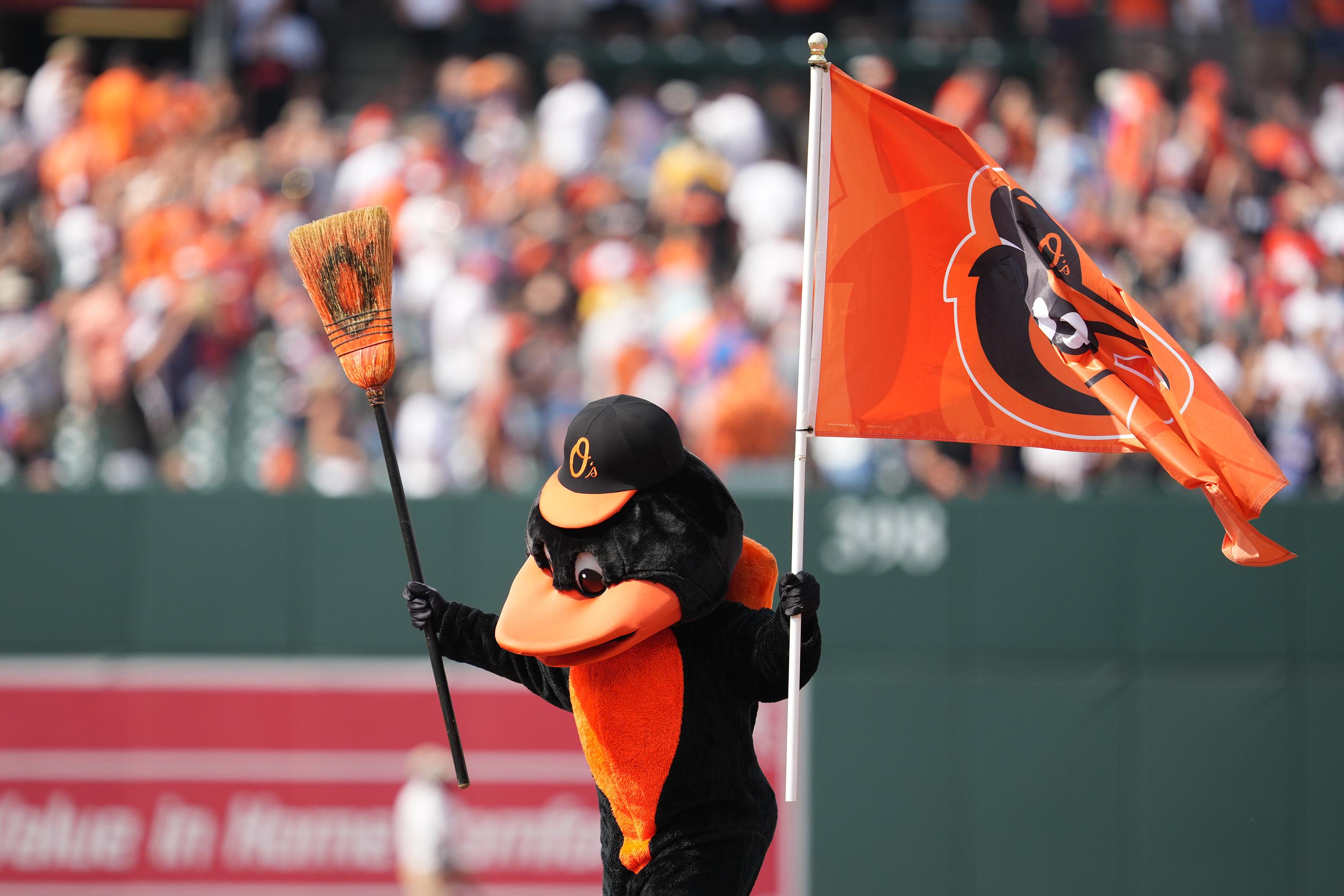 The Oriole Bird mascot shakes a broom and waves a flag with the O's logo on it.