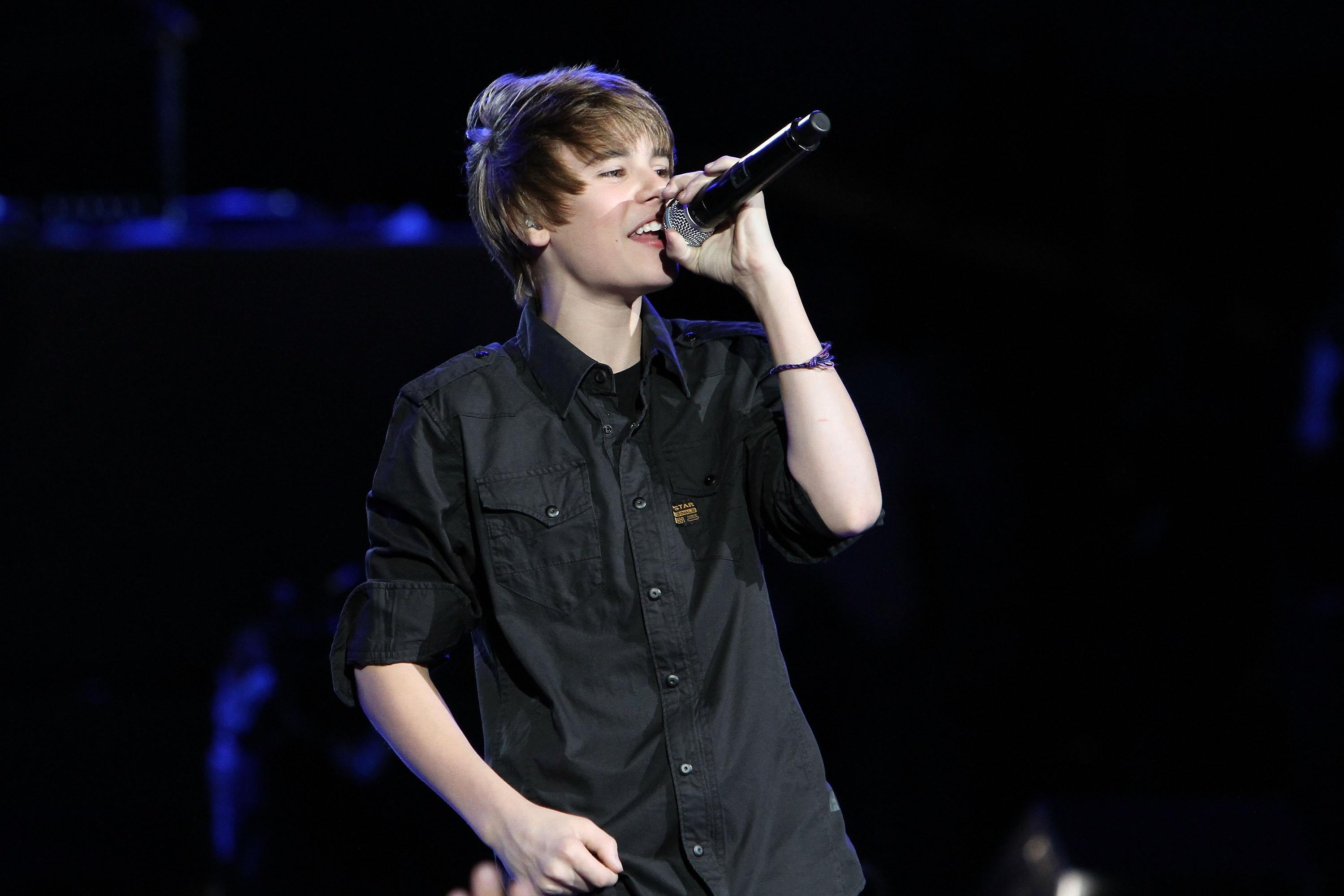 Justin Bieber holds a microphone onstage.