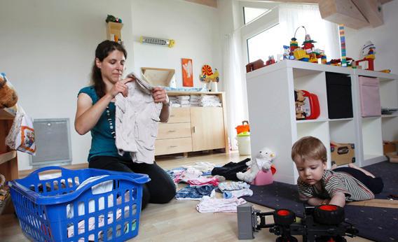 Claudia folds clothes in the playroom next to son Michael at home in Durach, southern Germany.