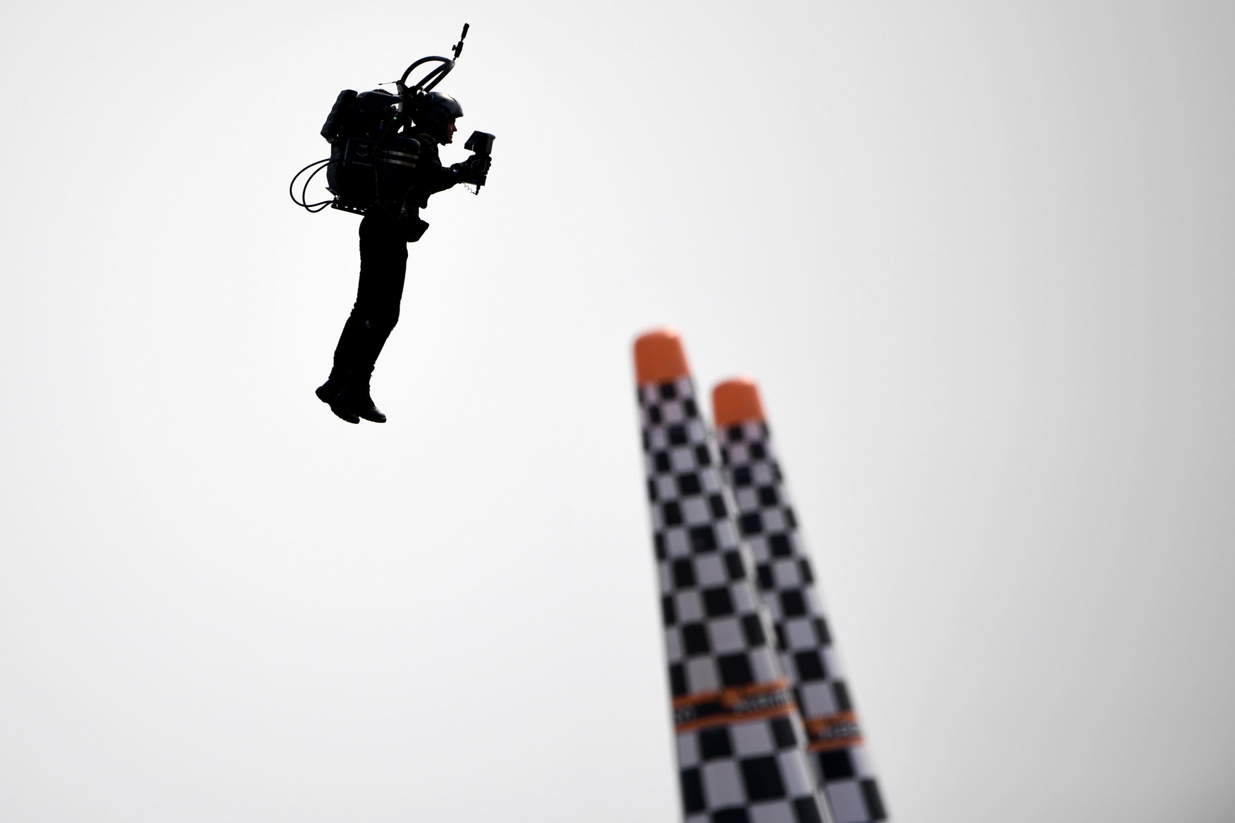 A man flies near two poles.