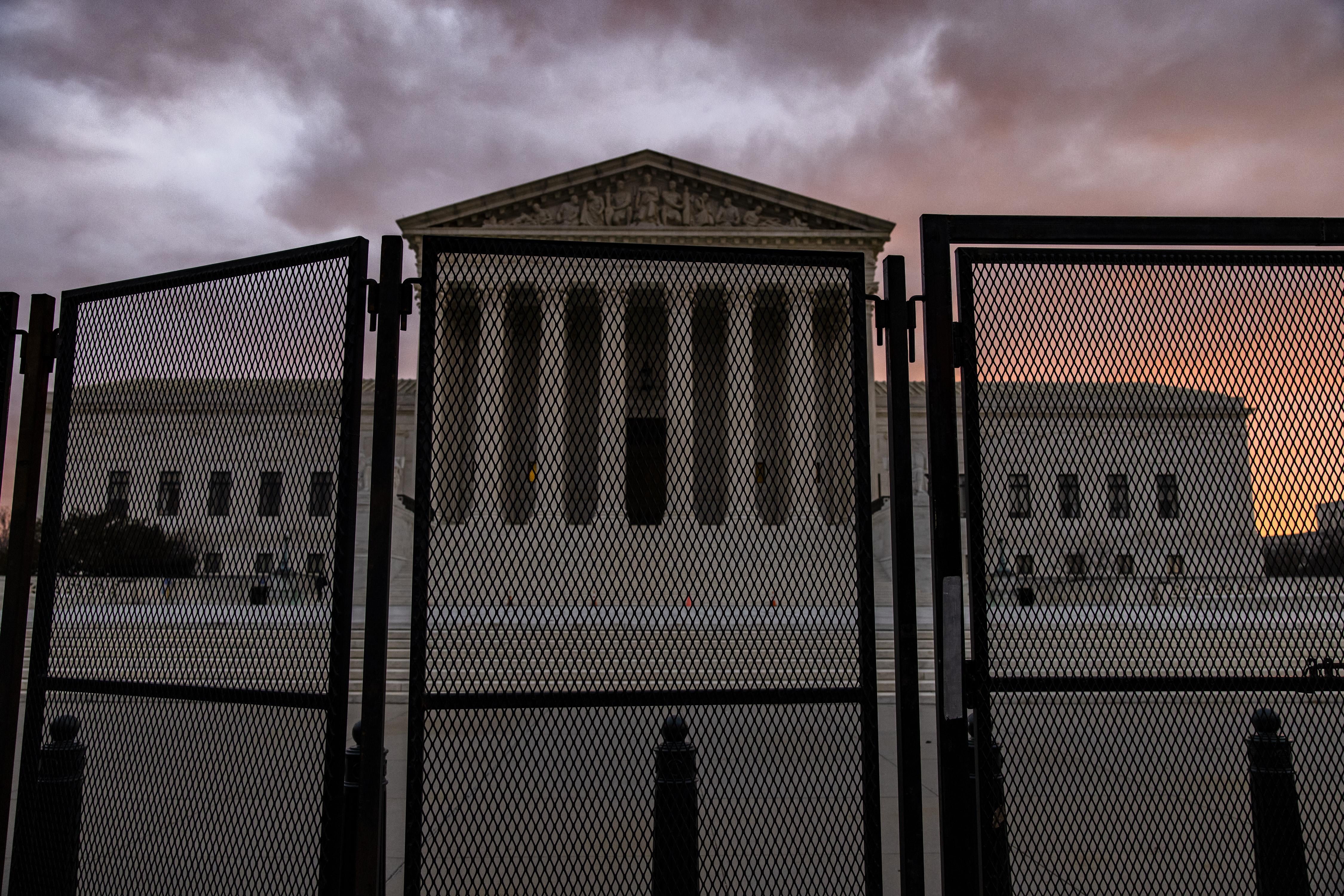 The Supreme Court at dusk, with a large fence around the building.