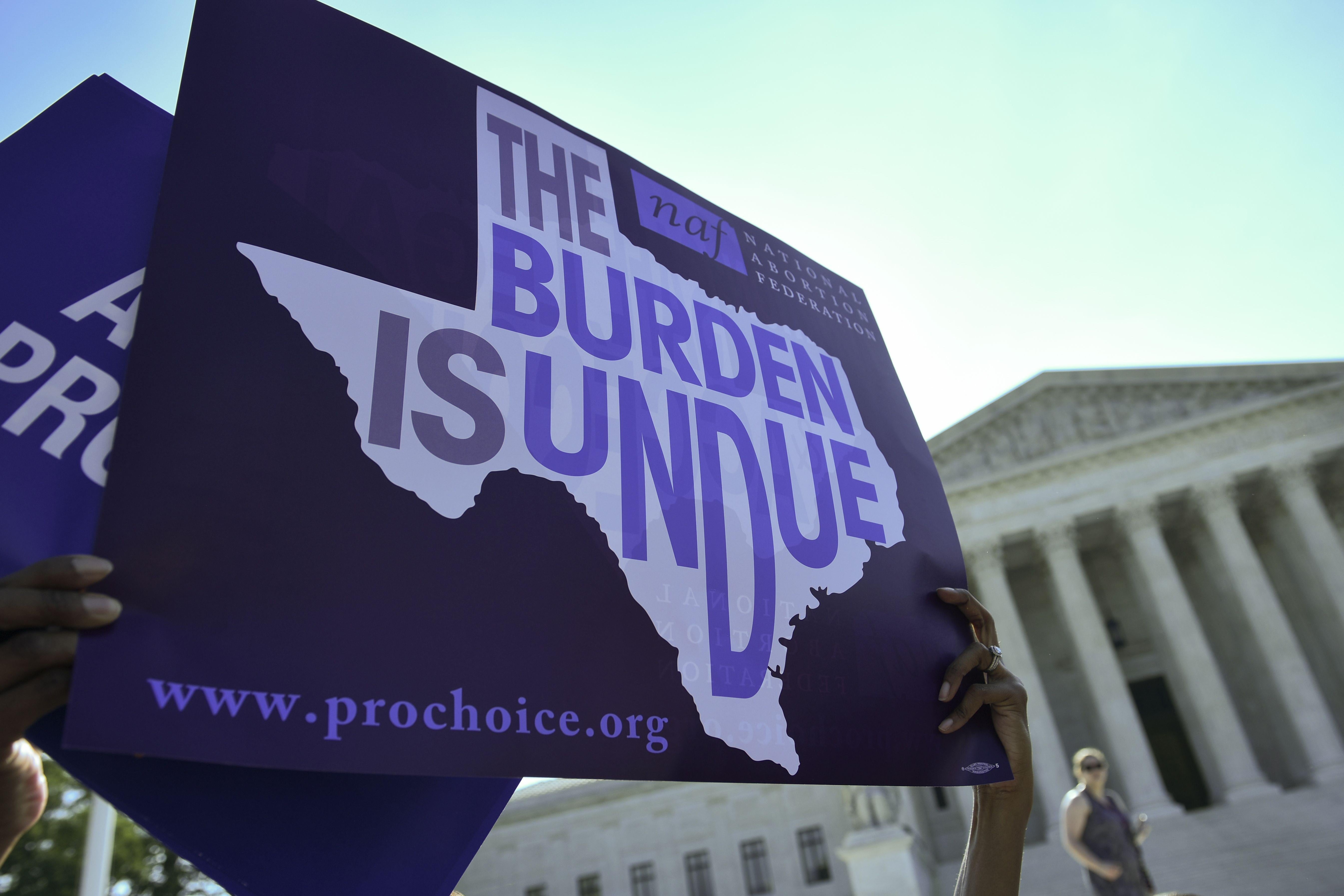 An abortion rights activist holds a placard that reads "The Burden Is Undue" outside of the Supreme Court.