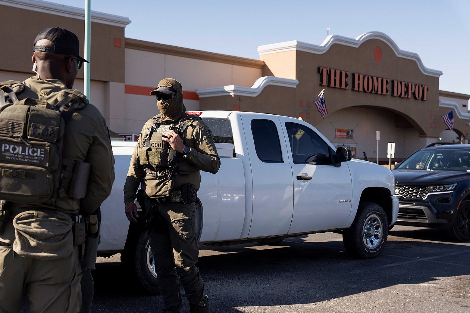 ICE agents in full tactical gear and masks chatting outside the doors of a Home Depot