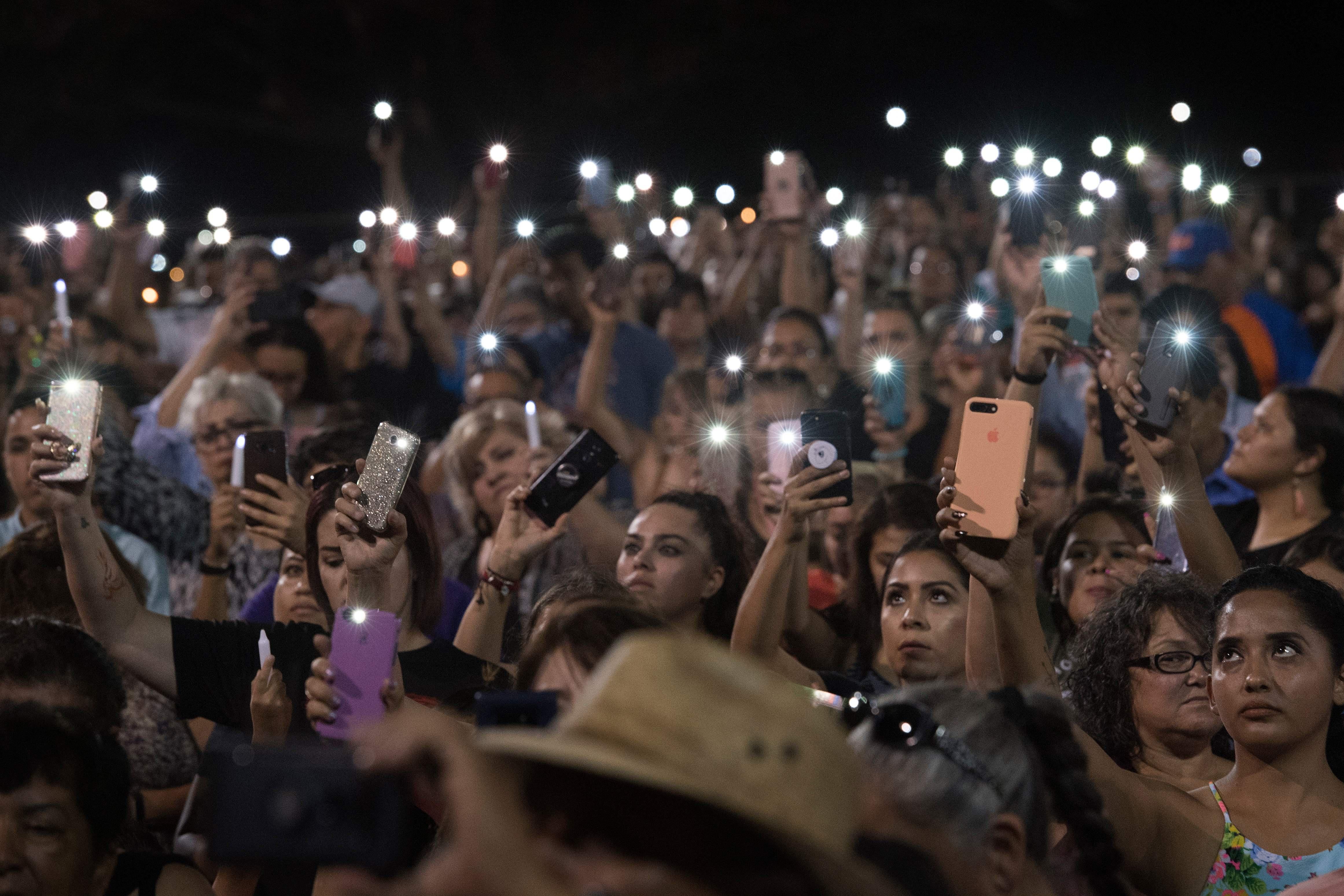 People hold up their phones during a vigil.