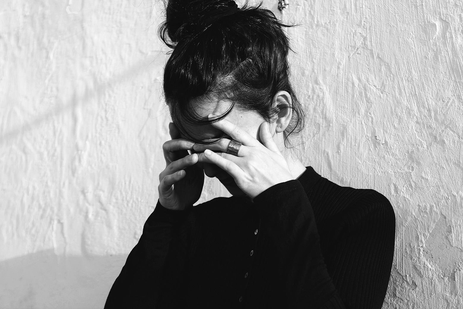 Black and white photo of a woman covering her face as if in despair