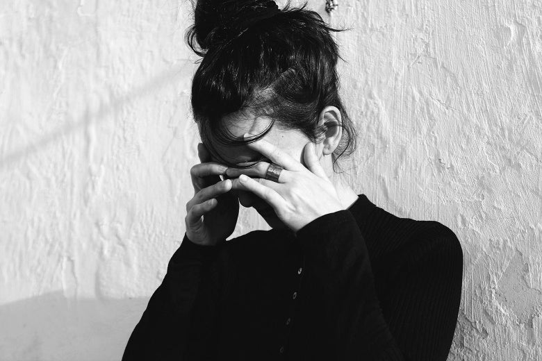 Black and white photo of a woman covering her face as if in despair
