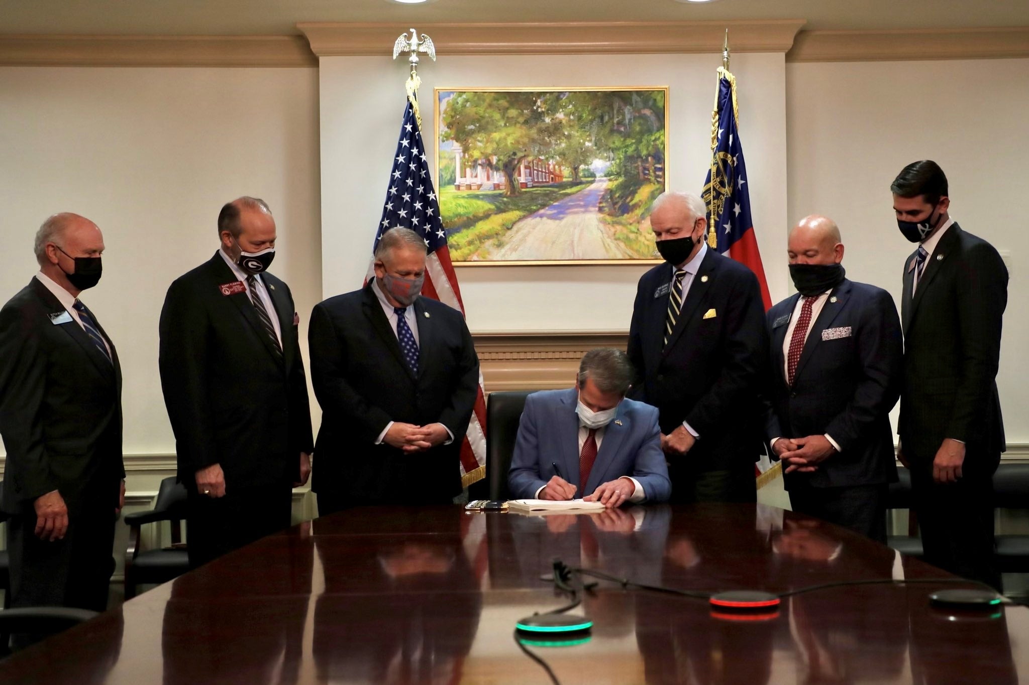 Georgia Gov. Brian Kemp sits at a table surrounded by a handful of white men, as he signs a new restrictive voting law making it harder to vote.
