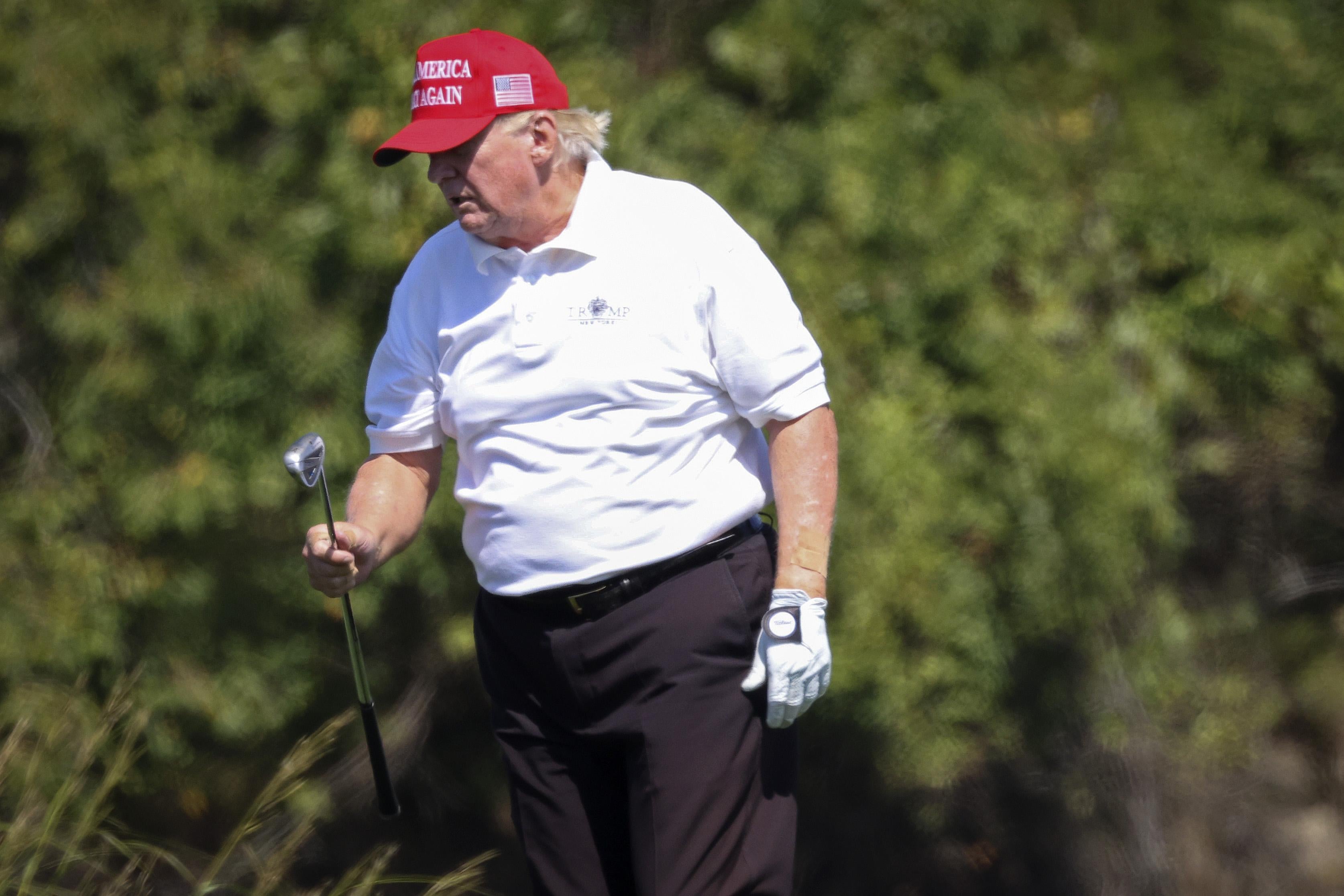 Donald Trump holding a golf club and looking rough.