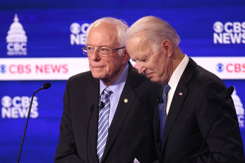 Biden smiles while standing next to Sanders at Sanders' lectern.