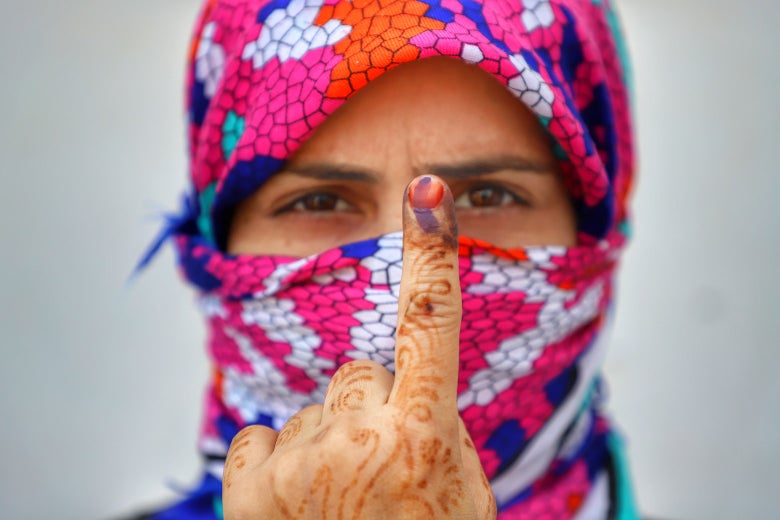 A woman in bright headscarf holds up her inked index finger after casting her vote during the first phase of general elections in the state of Uttar Pradesh, India, on Thursday.