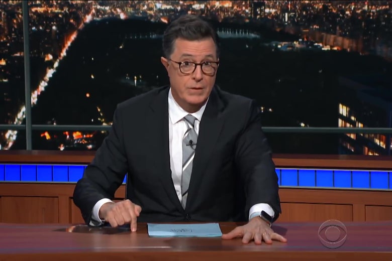 Stephen Colbert sitting behind a desk.