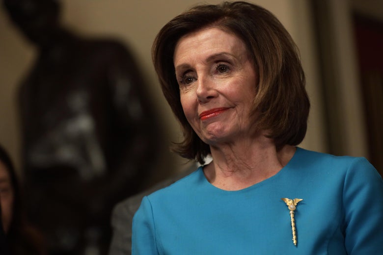 Nancy Pelosi in a blue dress with a gold pin.