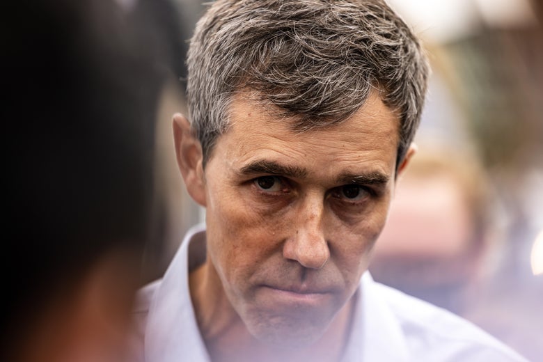 A close-up of Beto O'Rourke with head slightly bowed, looking up, with dark circles under his eyes