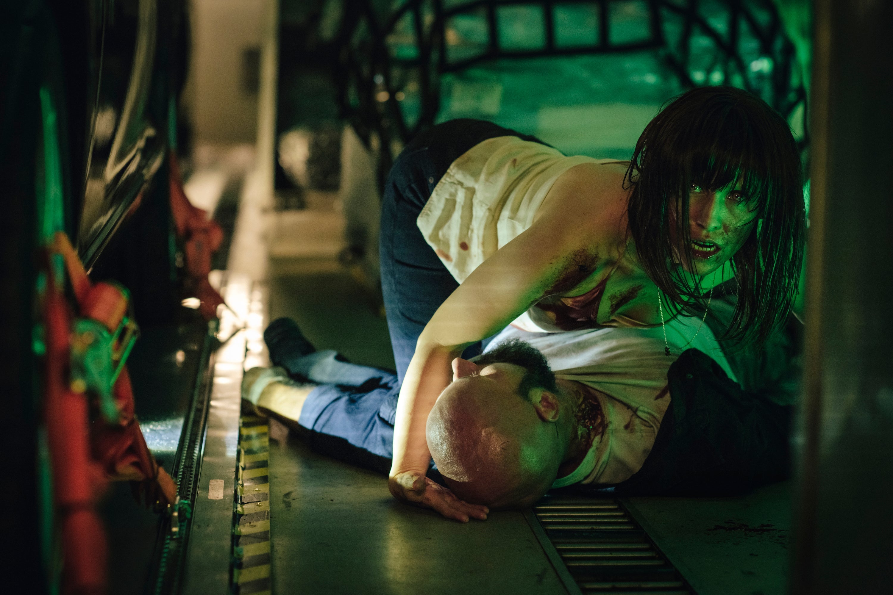a woman crouches above a prone man's body
