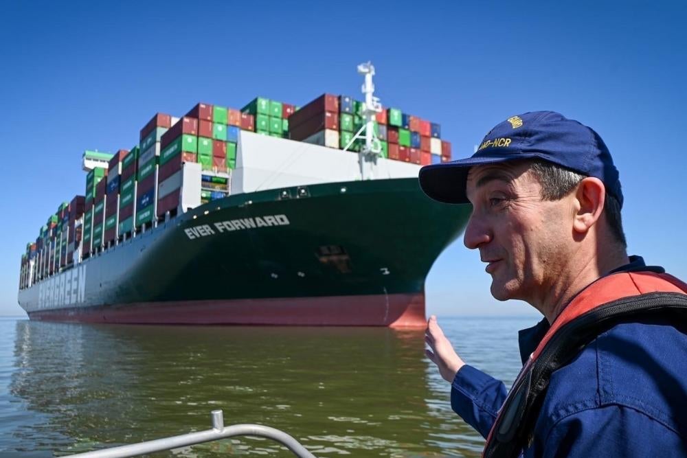 A man gestures toward a giant cargo ship on the water