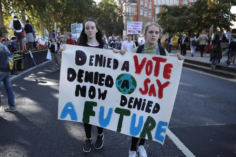 Two girls hold a sign that says "Denied a vote, denied a say, now denied a future."