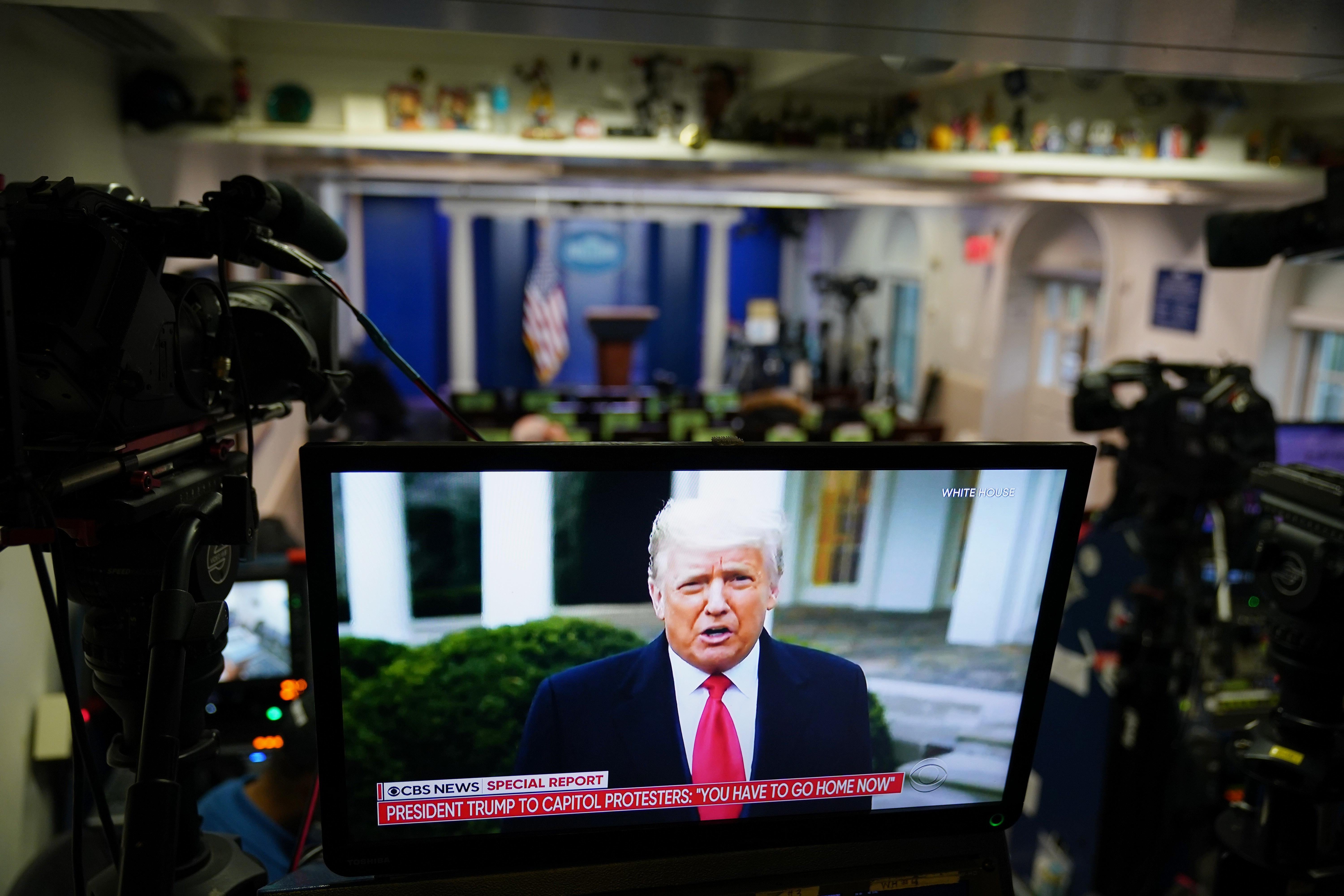 A TV screen at the rear of the White House press room shows Donald Trump speaking.