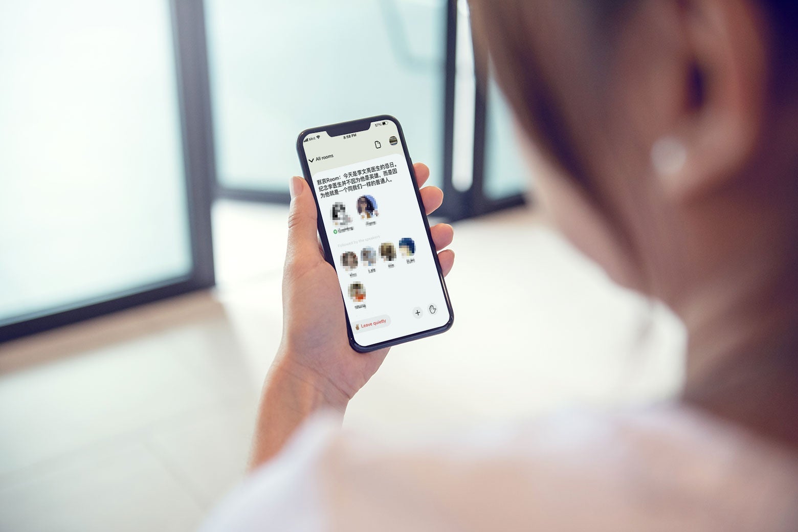 A woman looking at the Clubhouse app on her phone.