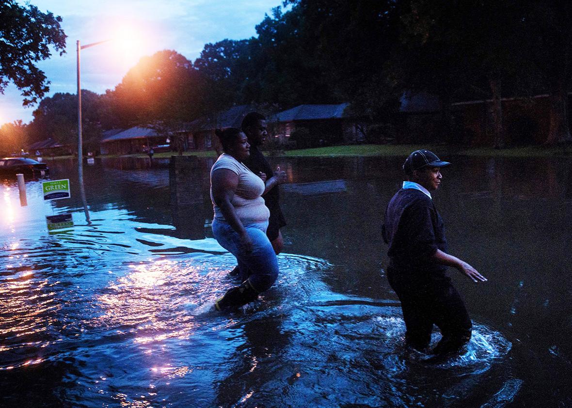 People walk through a flooded neighborhood August 15, 2016 in Baton Rouge, Louisiana.