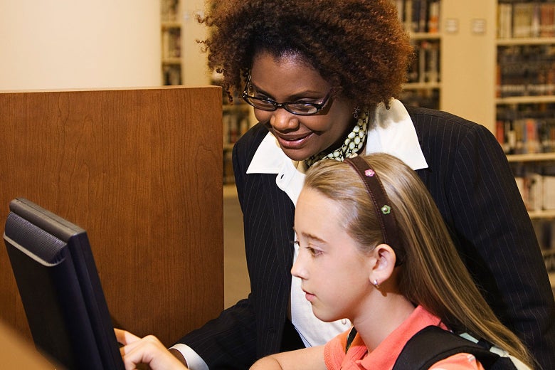 A librarian helping a girl with a computer.