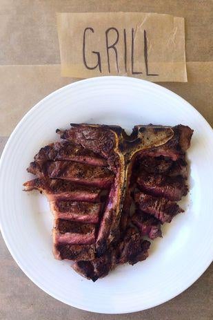 A T-bone steak on a plate next to a sign labelled "Grill."