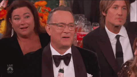 Tom Hanks at the Golden Globes looking appalled, then sadly staring down at the table.