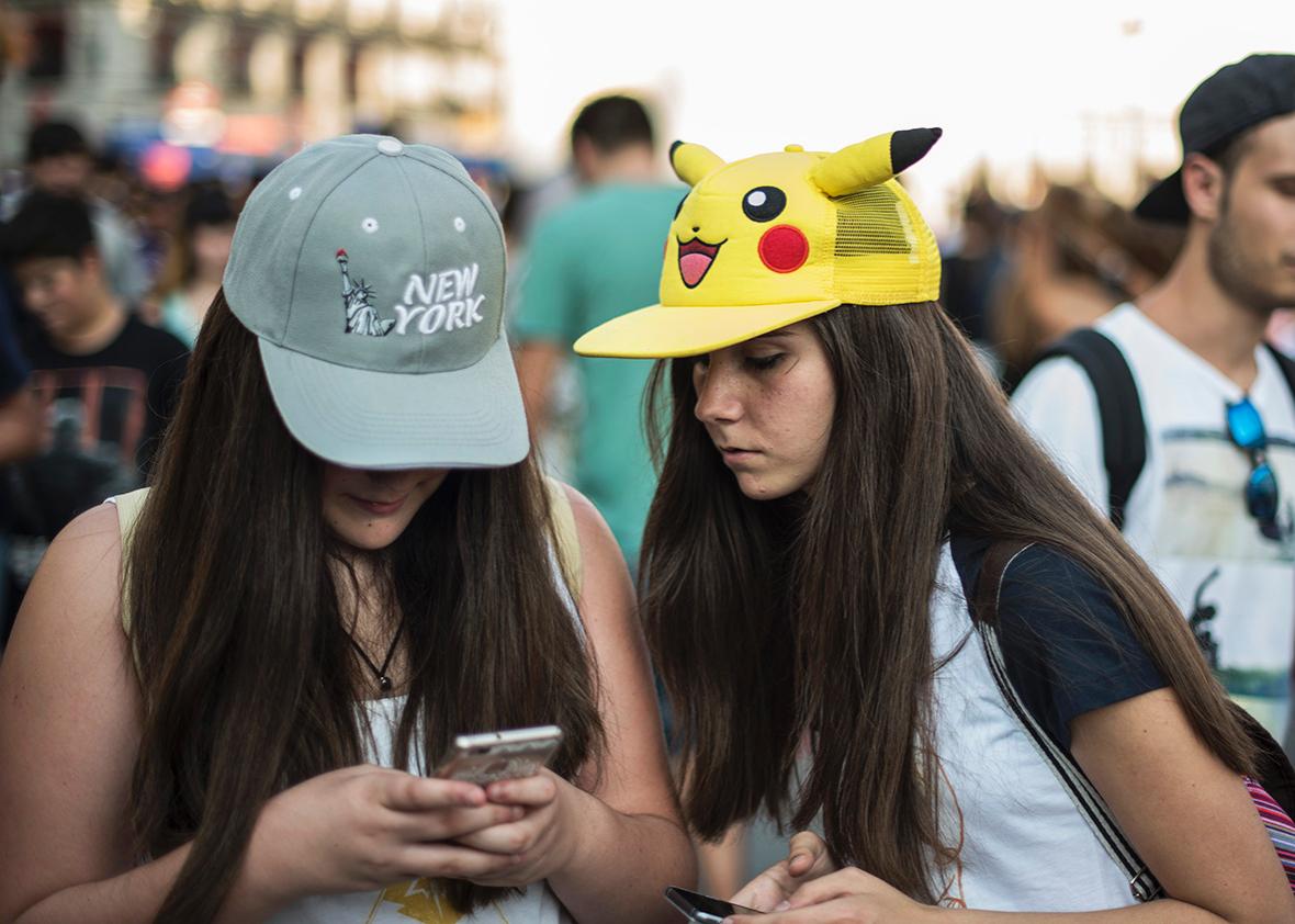 A girl sporting a Pikachu hat looks at her friend as she plays Pokémon Go in Madrid on Thursday.