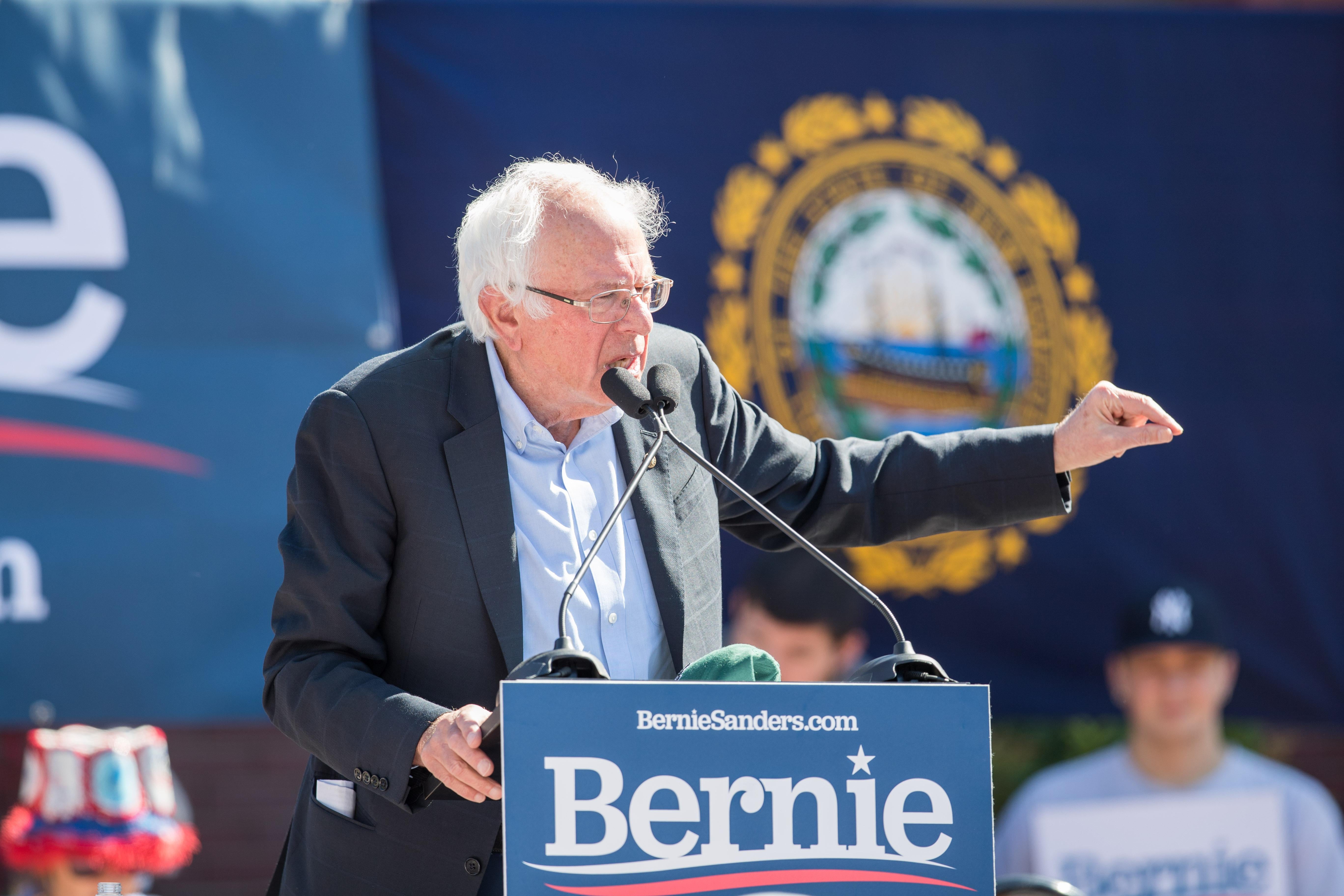 Bernie Sanders speaks from a podium at a political rally.
