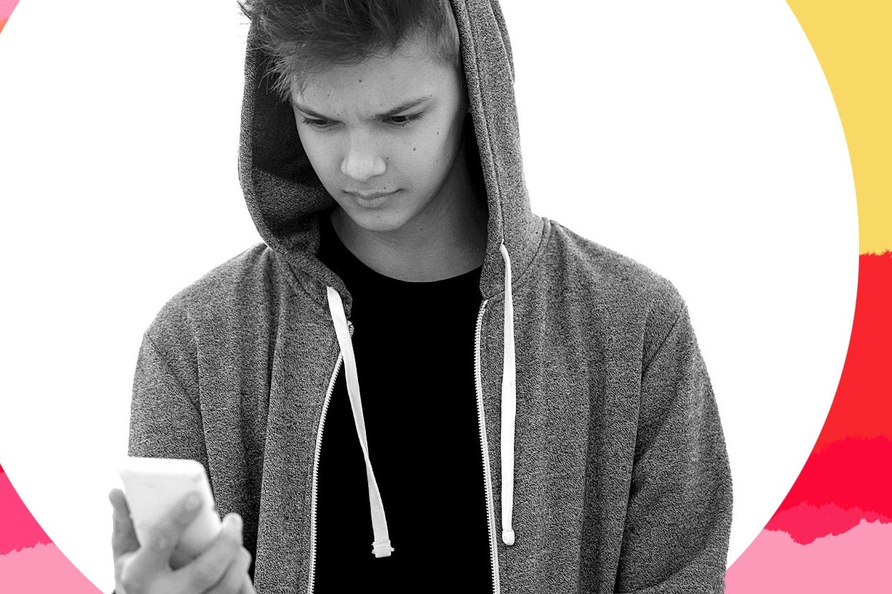 A teenage boy looks at his phone.