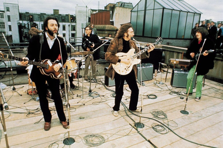 Four men play their instruments on a rooftop.