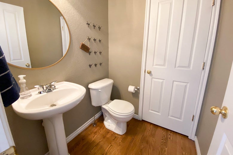 Slightly Western-themed bathroom with a white toilet and sink. Lights are on. The bathroom looks really clean.
