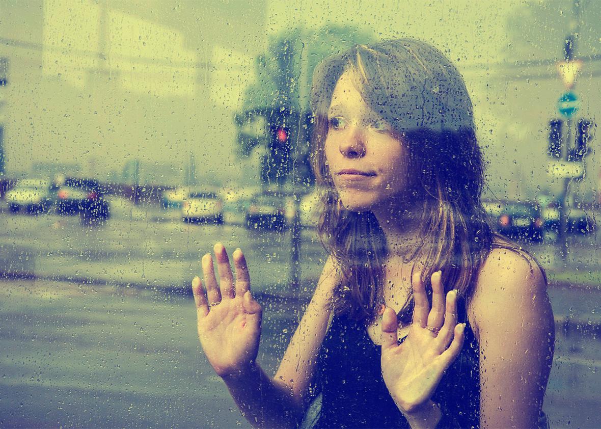 A woman presses her hands up against a glass window.