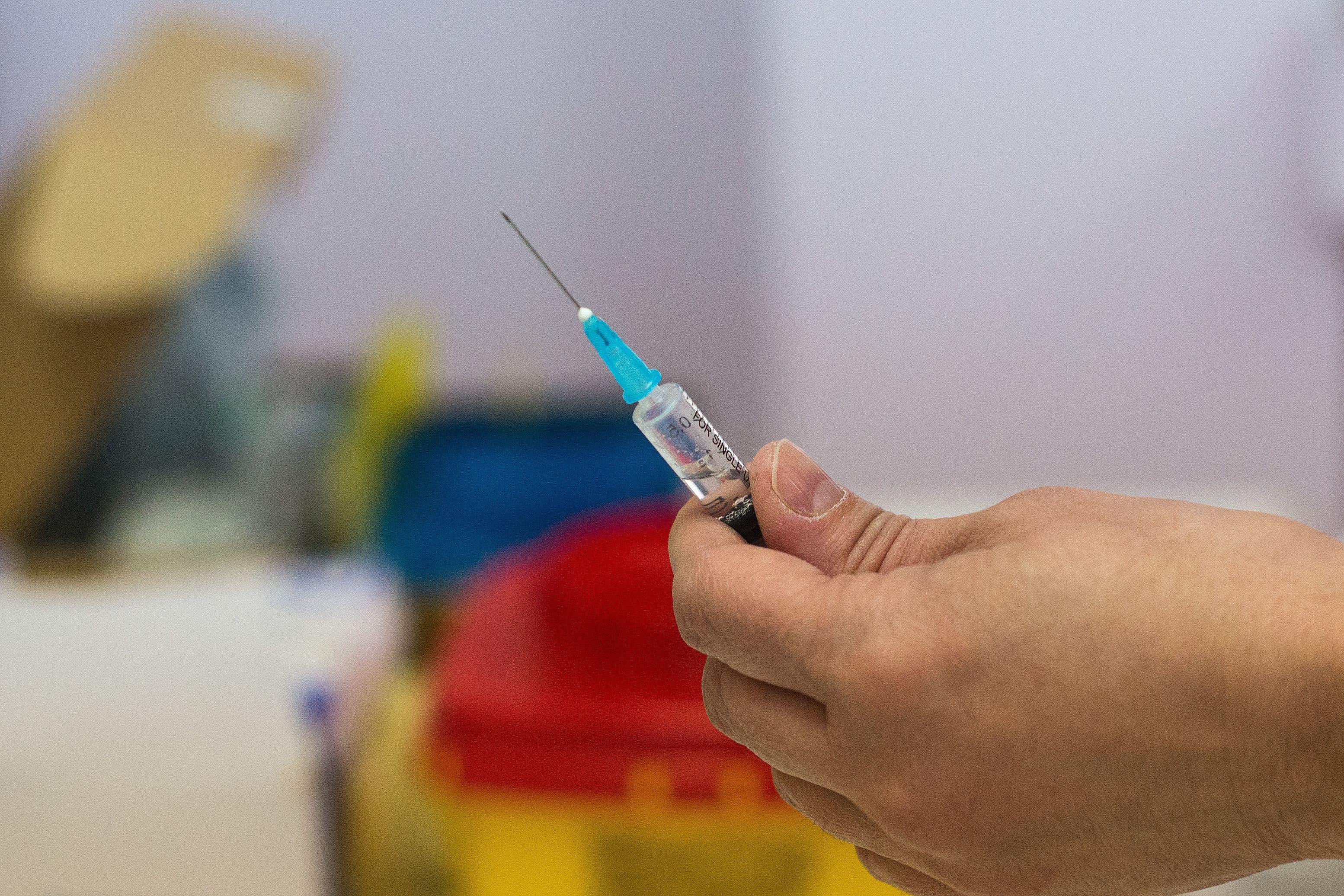 A hand holds a vaccination needle.