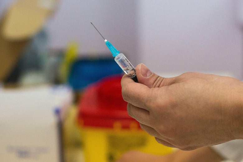 A hand holds a vaccination needle.