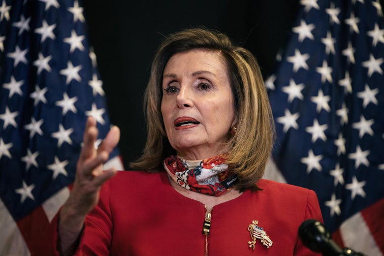Nancy Pelosi holds up her right hand as she speaks in front of American flags.
