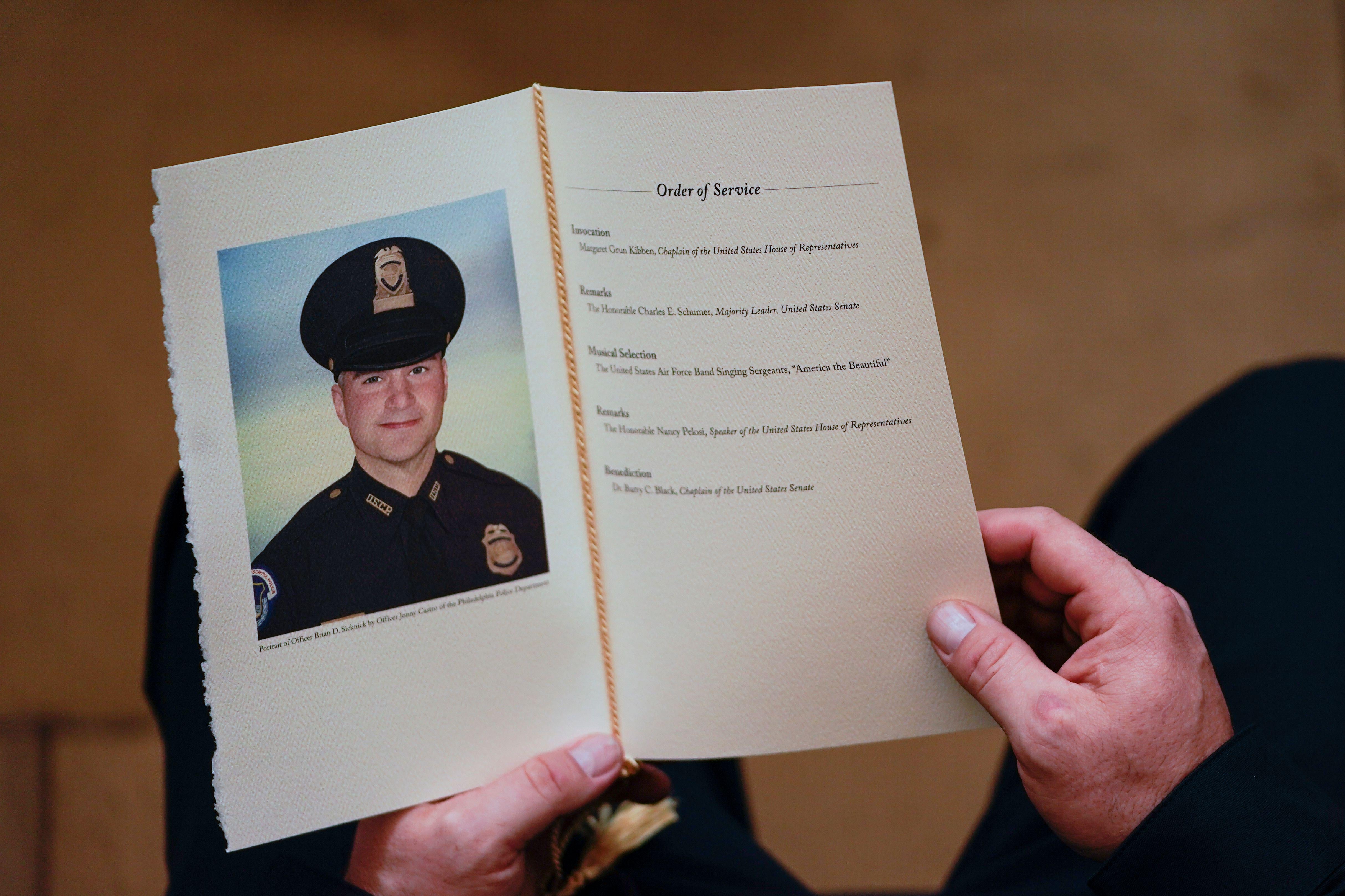 Hands holding a program open to a photo of Brian Sicknick