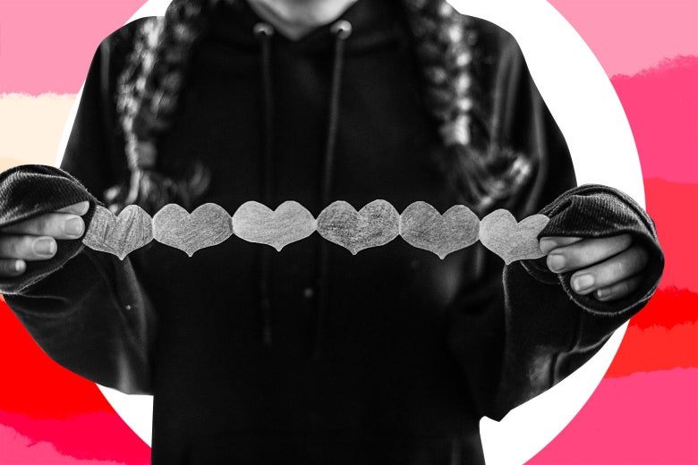 A young girl holds a string of paper hearts.