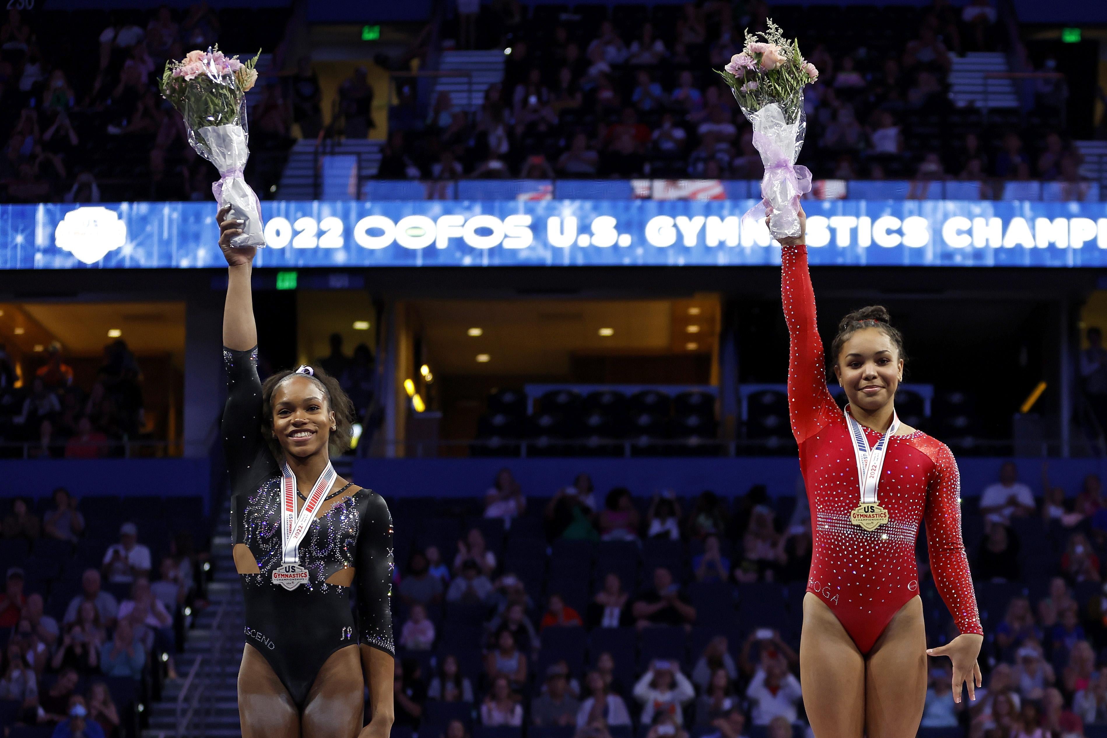 Jones and McClain lift bouquets and smile on the podium with medals around their neck