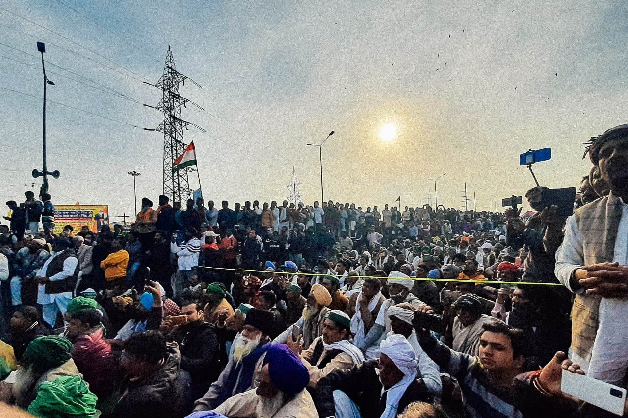 A crowd of people with a hazy sun in the background.
