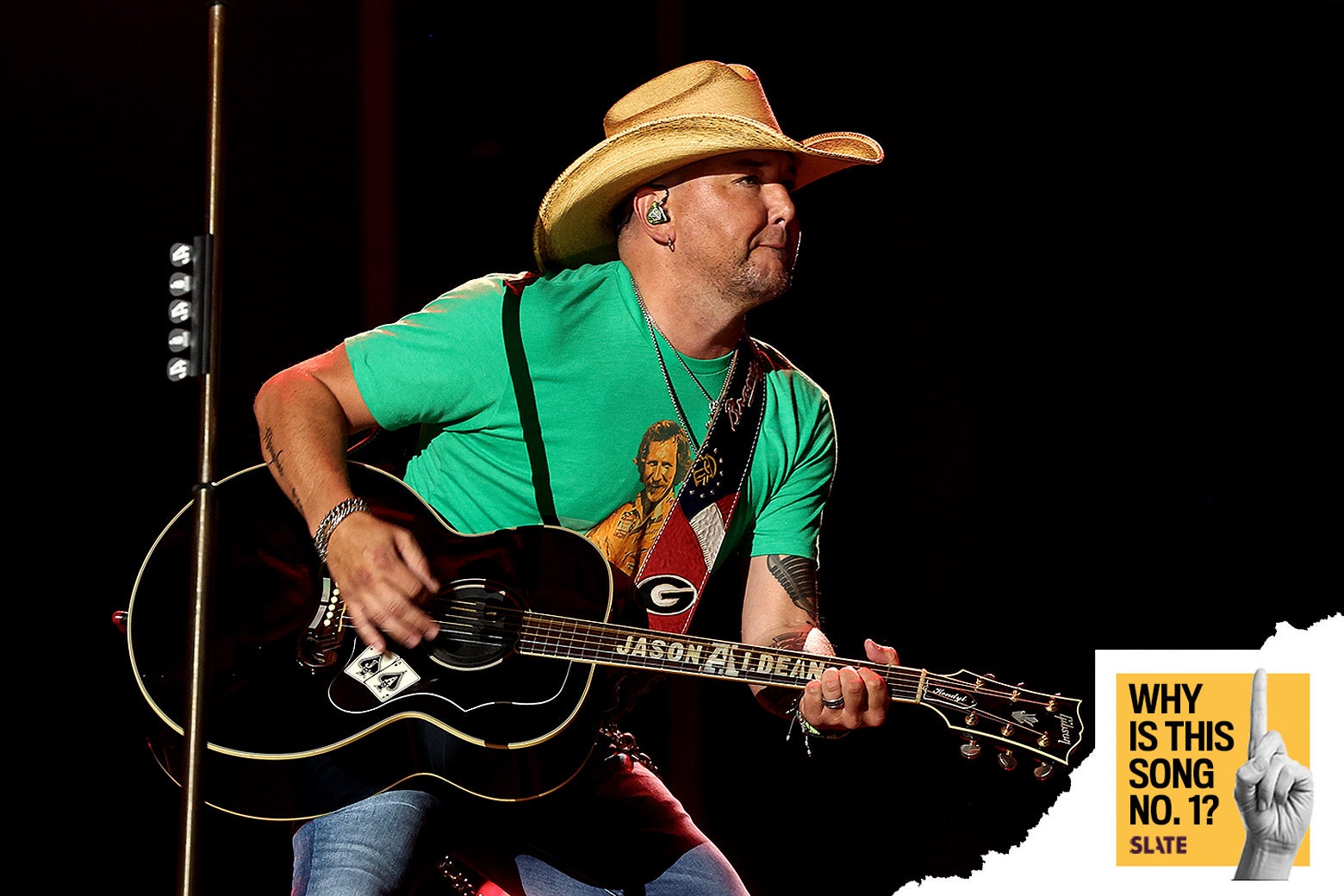 Jason Aldean leans forward playing guitar on stage. 