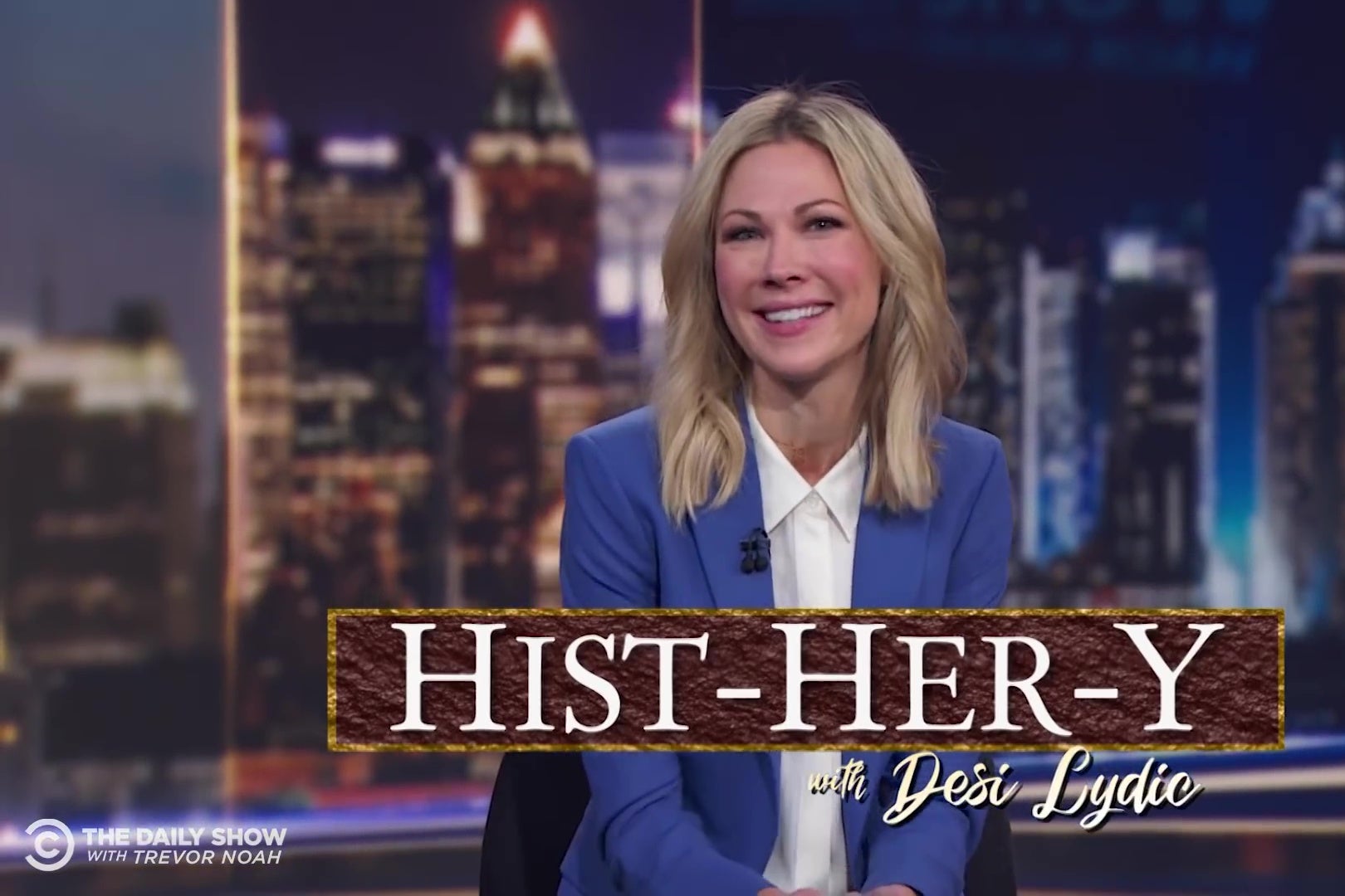Desi Lydic sits at the anchor desk; the words "Hist-HER-y with Desi Lydic" are superimposed on the image.