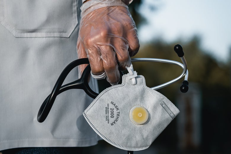 A gloved hand holds a stethoscope and mask
