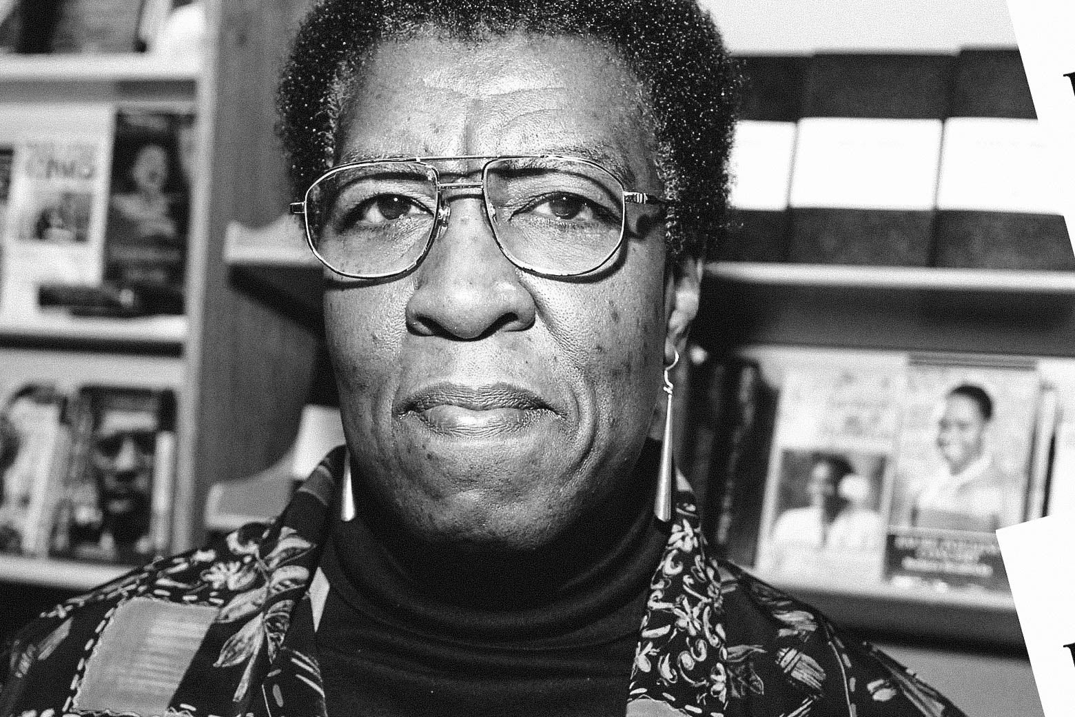 A black-and-white photo of Octavia E. Butler, wearing wire-frame glasses and a printed collared shirt.